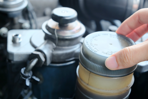 Close up view of a brake fluid cap being screwed off
